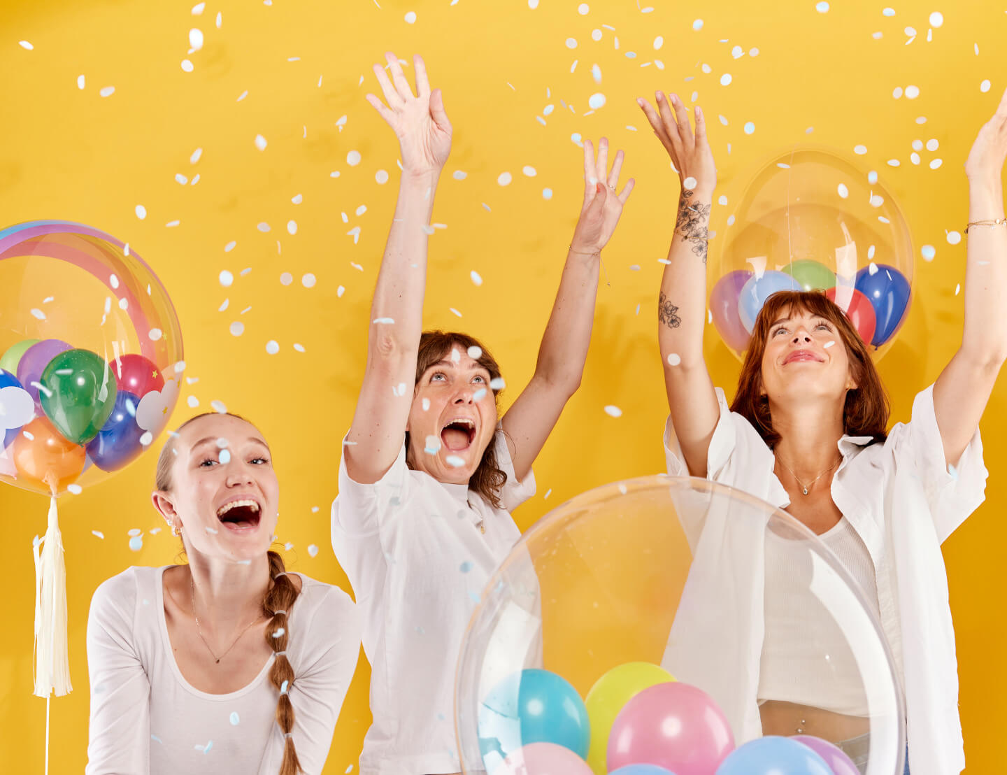 Frauen streuen Konfetti, schwebende Ballons